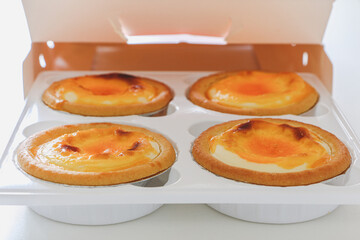 Delicious golden Chinese custard egg tarts (danta) out of its box, a popular Chinese baked snack dessert originating from Guangzhou