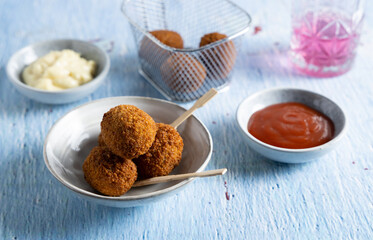 Fried meatballs in a bowl with ketchup on the side.