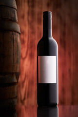 red wine bottle next to barrel with white etiquette on dreamy vine back drop
