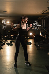 Athletic woman getting ready to do barbell squat in crossfit gym, hard workout. Sportswoman doing...