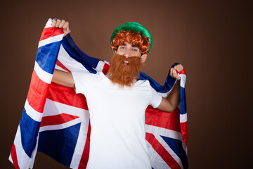 St.Patrick 's Day. Funny guy in a leprechaun costume posing on a brown background.