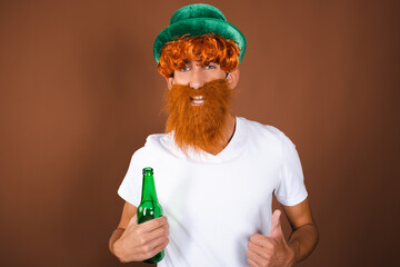 St.Patrick 's Day. Funny guy in a leprechaun costume posing on a brown background.