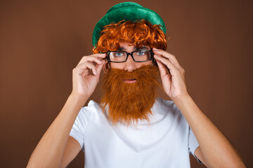 St.Patrick 's Day. Funny guy in a leprechaun costume posing on a brown background.