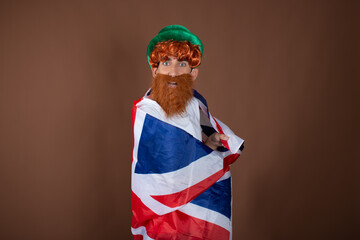St.Patrick 's Day. Funny guy in a leprechaun costume posing on a brown background.