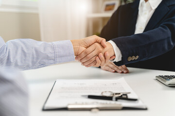 Top view hands of agent and client shaking hands after signed contract buy new apartment.