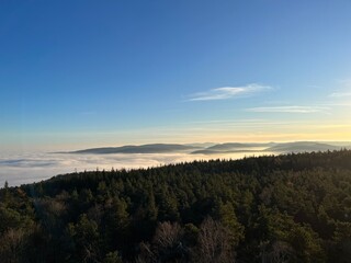 Afternoon sunlight illuminating the fog-covered valleys and the hills of Germany's Palatinate Forest on a cold winter's day