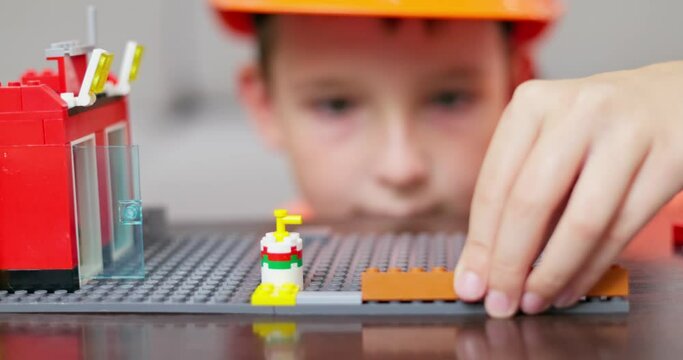 Child hands play with colorful plastic toy bricks and constructor game blocks.