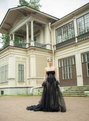 A 30-year-old girl in a black transparent revealing dress is walking on the street near her house. Style and elegance, femme fatale, photo shoot in a black dress, advertising