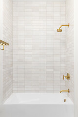 A shower and bathtub with brown subway tiles and a gold showerhead and faucet.