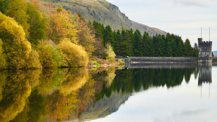 Fototapeta na wymiar Autumn reflections at Llwyn-on,or Llwyn Onn Reservoir. The leaves have changed colour along the edge of the largest of three reservoirs in the Taf Fawr valley in the Brecon Beacons and South Wales. 