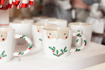 mugs with holly and santa claus minimal design at shelf at christmas market