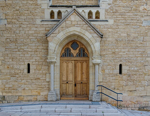 Fototapeta na wymiar Entrance of a small roman church, gold stones and wooden door, France