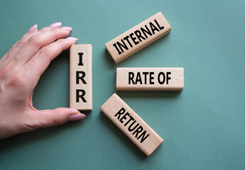 IRR - Internal Rate of Return symbol. Concept word IRR on wooden cubes. Businessman hand. Beautiful...