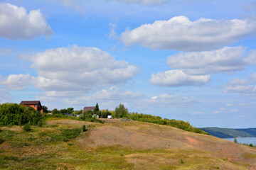 Fototapeta na wymiar hill with cottages and blue sky with clouds copy space 