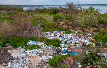 Heaps of plastic trash on the shore of the reservoir. Ecology of nature