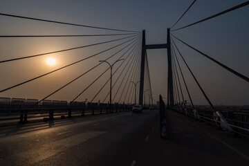 Cable stayed suspension bridge known as the Vidyasagar Setu built on the river Ganges at sunset with view of a boat seen from Princep Ghat at Kolkata, India - obrazy, fototapety, plakaty