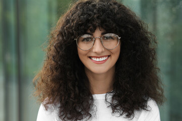 Portrait of beautiful woman in glasses on blurred background. Attractive lady smiling and looking into camera