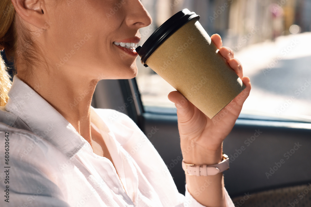 Wall mural To-go drink. Woman drinking coffee in car, closeup