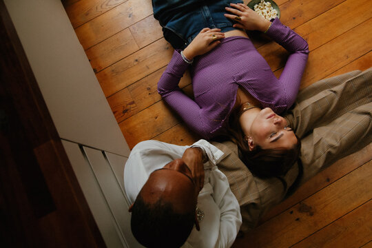 Young woman and non-binary person relaxing on kitchen floor
