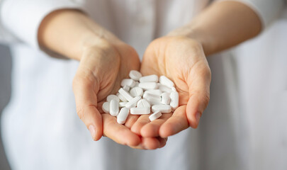 woman holding several vitamin pills and supplements in her hands