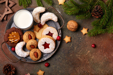 Christmas cookies and milk for Santa: linzer cookies with strawberry jam, crescents with sugar powder, almond cookies, chocolate cookies with condensed milk. Top view, blank space for text