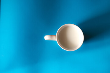 porcelain cup with milk on blue background top view