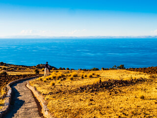 Stunning view of lake Titicaca at sunset, with a local farmer riding down to the village through a stone path, Amantani island, Peru
- 680637827