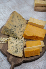 English cheeses collection, mature and coloured cheddar cheese and semi-soft, crumbly old stilton blue cheese close up