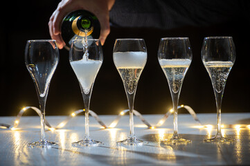 New year party, pouring of brut champagne bubbles cava or prosecco wine in tulip glasses with...
