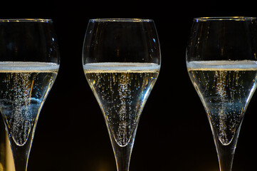 New year party, small bubbles of brut champagne cava or prosecco wine in tulip glasses with garland  lights on background