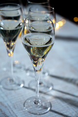 New year party, small bubbles of brut champagne cava or prosecco wine in tulip glasses with garland  lights on background