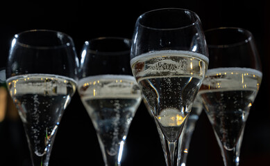 New year party, small bubbles of brut champagne cava or prosecco wine in tulip glasses with garland  lights on background