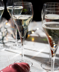 New year party, small bubbles of brut champagne cava or prosecco wine in tulip glasses with garland  lights on background