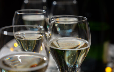New year party, small bubbles of brut champagne cava or prosecco wine in tulip glasses with garland  lights on background