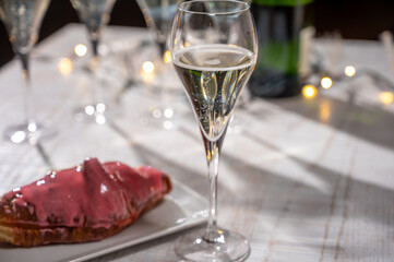 New year party, sweet dessert pink creamy croissant and brut champagne cava or prosecco wine in tulip glasses with garland  lights