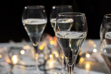 New year party, small bubbles of brut champagne cava or prosecco wine in tulip glasses with garland  lights on background