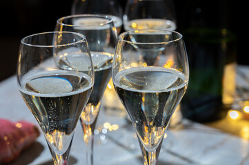 New year party, small bubbles of brut champagne cava or prosecco wine in tulip glasses with garland  lights on background