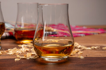 Tasting of different Scotch whiskies strong alcoholic drinks, drum of whiskey and colorful Scotch tartan on background close up