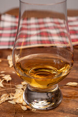 Tasting of different Scotch whiskies strong alcoholic drinks, drum of whiskey and colorful Scotch tartan on background close up