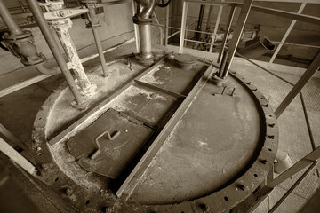 The cover of the tank with chlorine in the premises of the enterprise for the preparation of the city's drinking water supply, black and white image, sepia