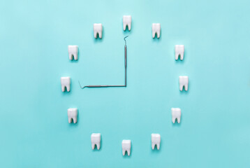 A clock made of teeth on a blue background and a dental probe. Flat lay. Dentistry. Place for text....