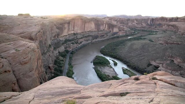 Wide shot of the Colorado River from the overlook at the end of a 4x4 trail in Moab Utah. Shot late in the day near sunset. Features a bend in the river with red rock cliffs along the shore.