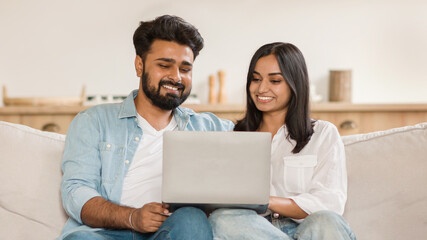 Happy indian couple smiling while looking at a laptop