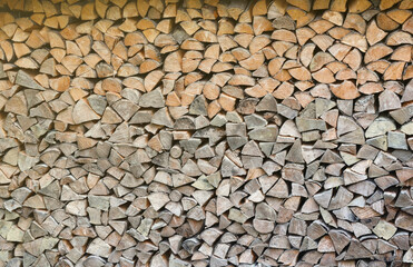 Firewood stacked near the wooden wall of old hut. Many chopped logs of firewood close up