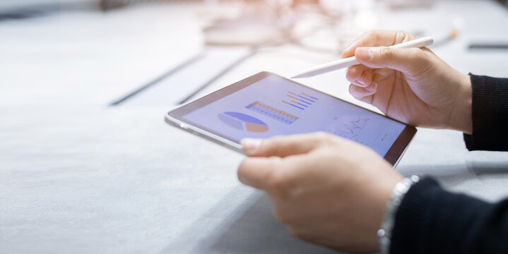 close up manager of marketing department use stylus pen to write or check summary profit report and performance of company on tablet in meeting office room for finance and roi of business concept