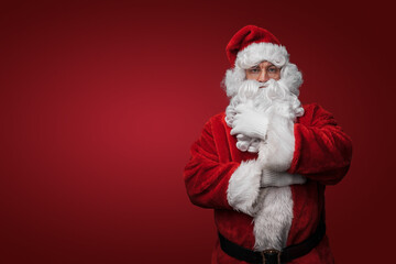 Shot of bearded santa with red winter costume looking at camera.