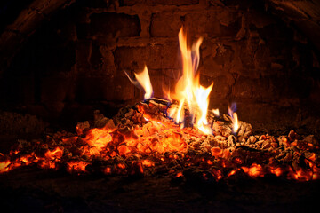 Logs of firewood burn out in the oven. Coals and flames in the fireplace.