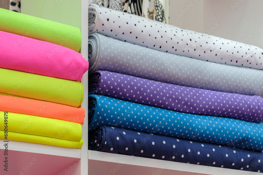Poster Shelf with a wide selection of colorful fabrics. Colorful ribbons on the shelf in the store. Textile industry