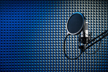 Professional microphone on the stand. Recording studio with acoustical wall panel.