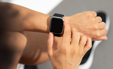 Cropped shot of fitness guy taps smartwatch on wrist, studio - obrazy, fototapety, plakaty